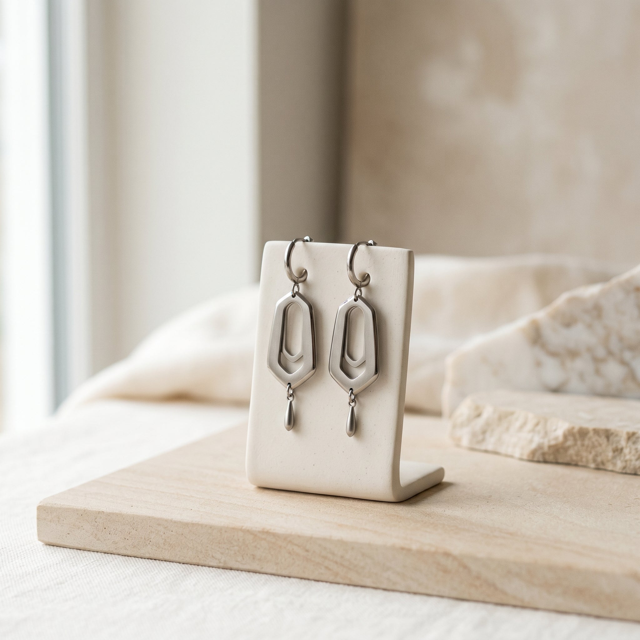 Titanium earrings arranged on a neutral surface for a sensitive ears guide.