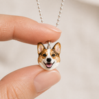 Two centimeter enamel corgi pet pendant held between fingertips for scale.